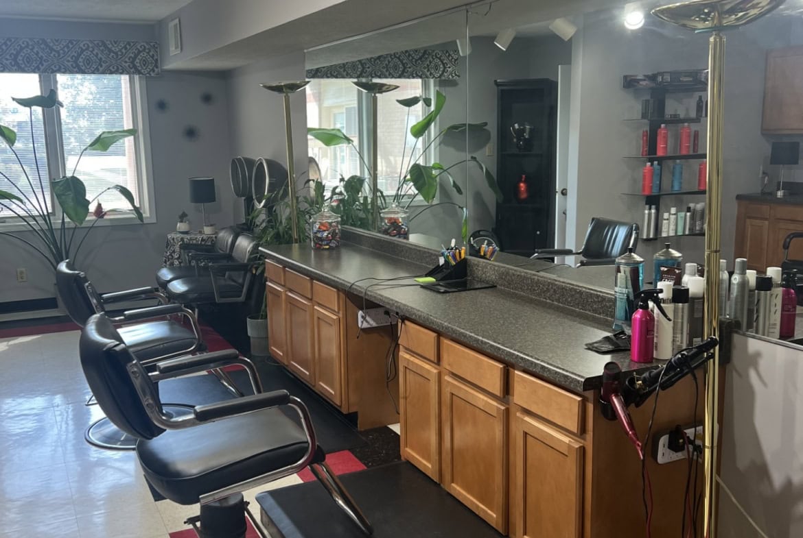 Modern salon hair station with chairs, mirrors, and styling tools.