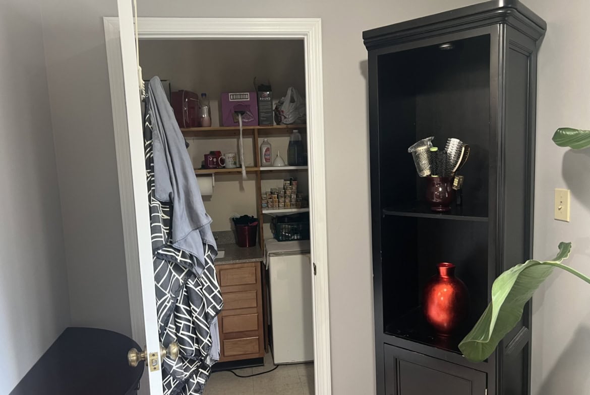 Interior view of a salon storage closet with shelves, towels, and supplies.