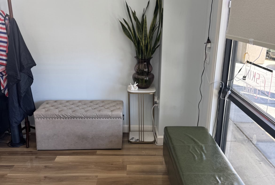 Waiting area with green bench and tall plant in salon.