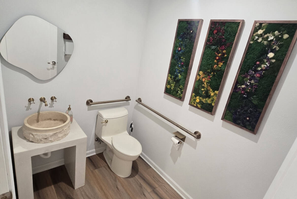 Accessible bathroom with a toilet, sink, and grab bars for salon professionals and clients.