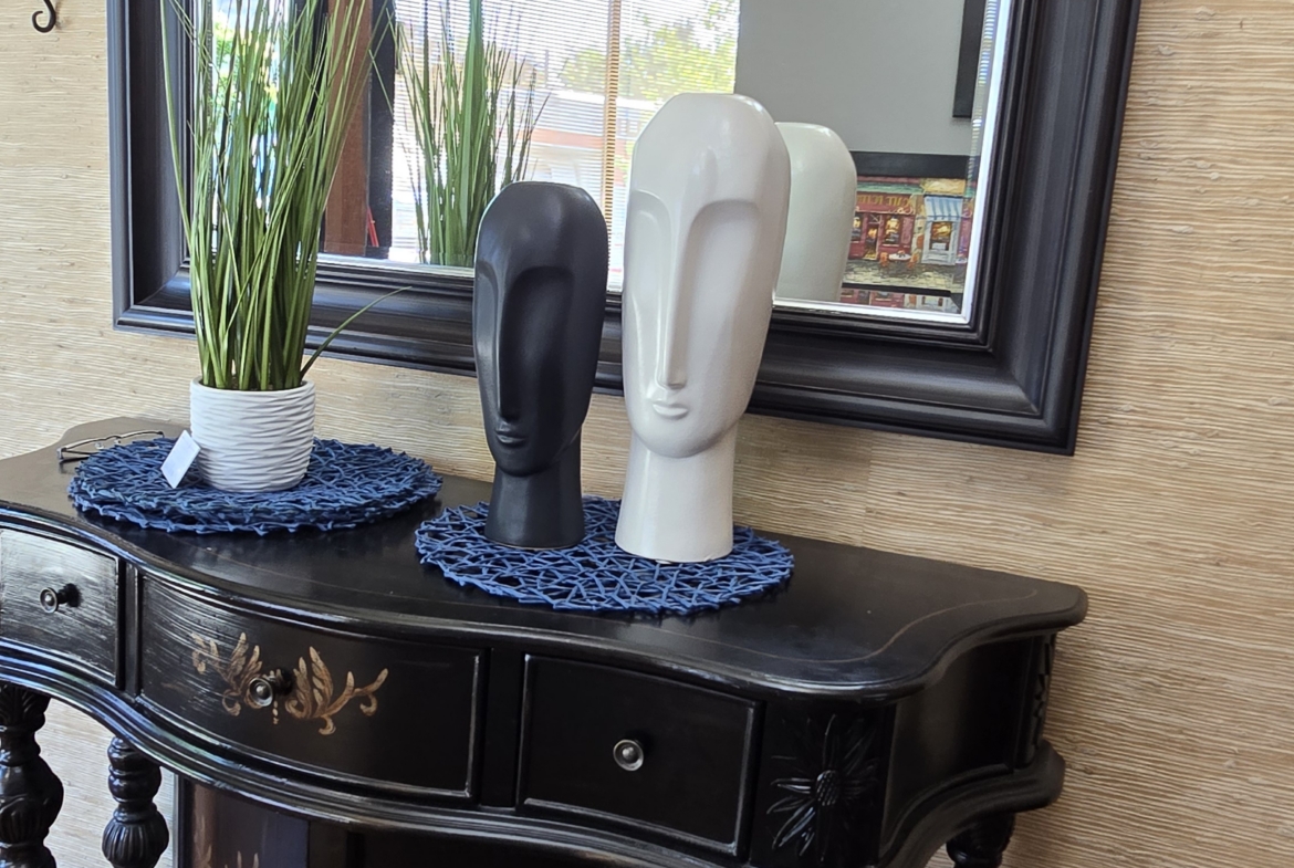 Elegant black console table with sculptures and mirror for salon interior design.