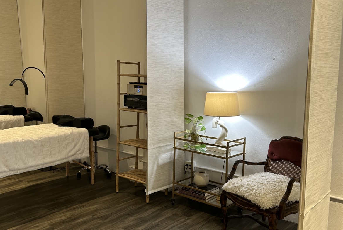 Relaxing salon waiting area featuring a comfortable chair, side table with lamp, and decorative plan.