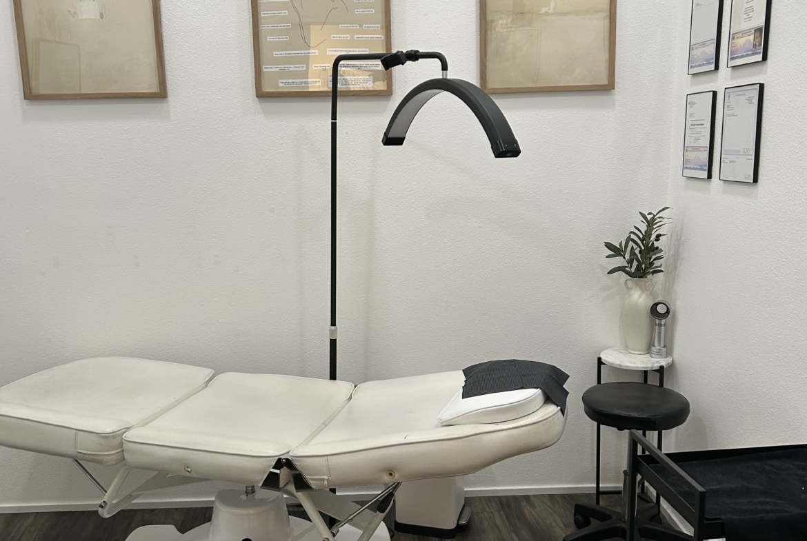Treatment room with massage table, professional lighting, and decor for salon or spa services.