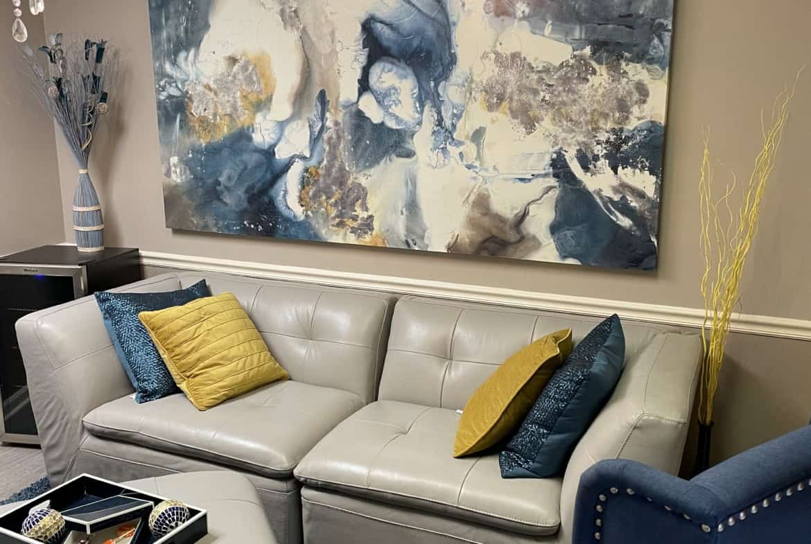 Stylish salon waiting room with abstract artwork, cozy sofa, and decorative pillows.