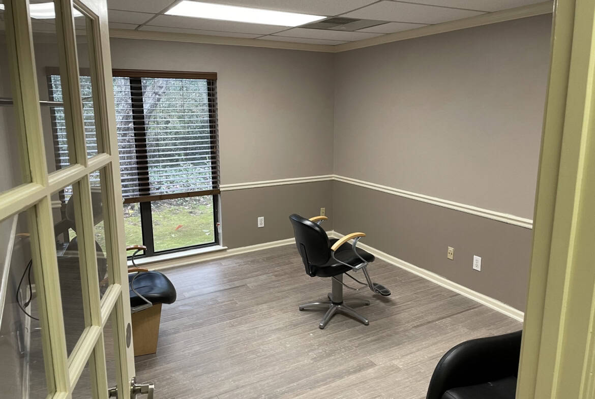 Salon rental room with large window, empty space, and professional setting.
