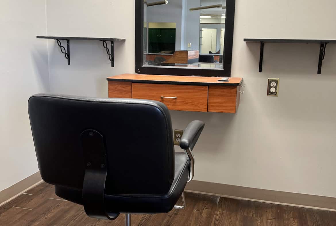 Styling station with mirror and salon chair for hairdressing or barber services.