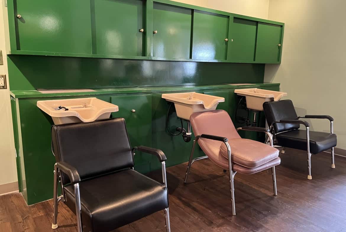 Hair washing stations with comfortable chairs and sinks in a salon setting.