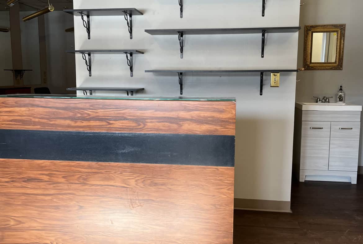 Stylish salon retail shelving unit with wooden counter and wall-mounted black metal brackets for pro.
