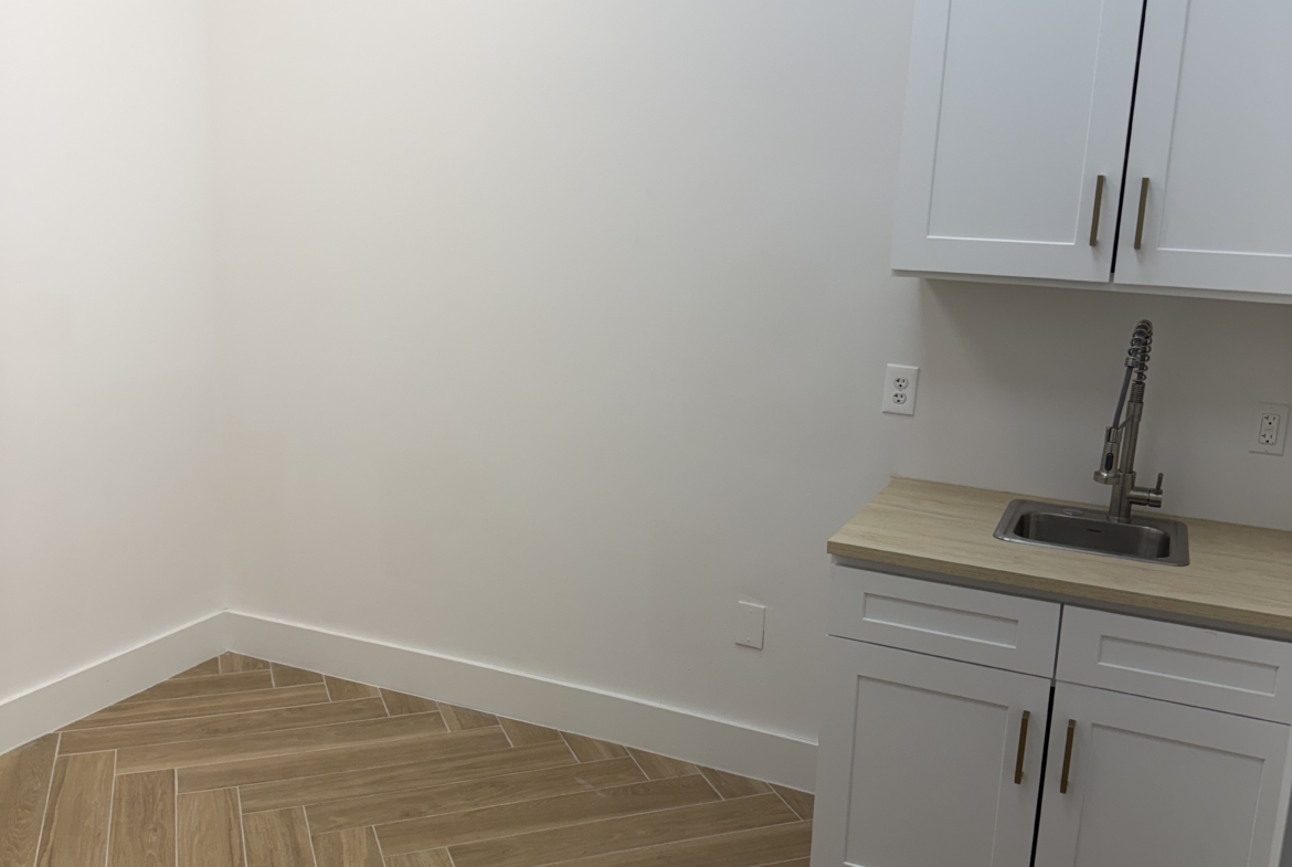 Salon Renter kitchenette with white cabinetry and wood-style flooring for salon professionals.