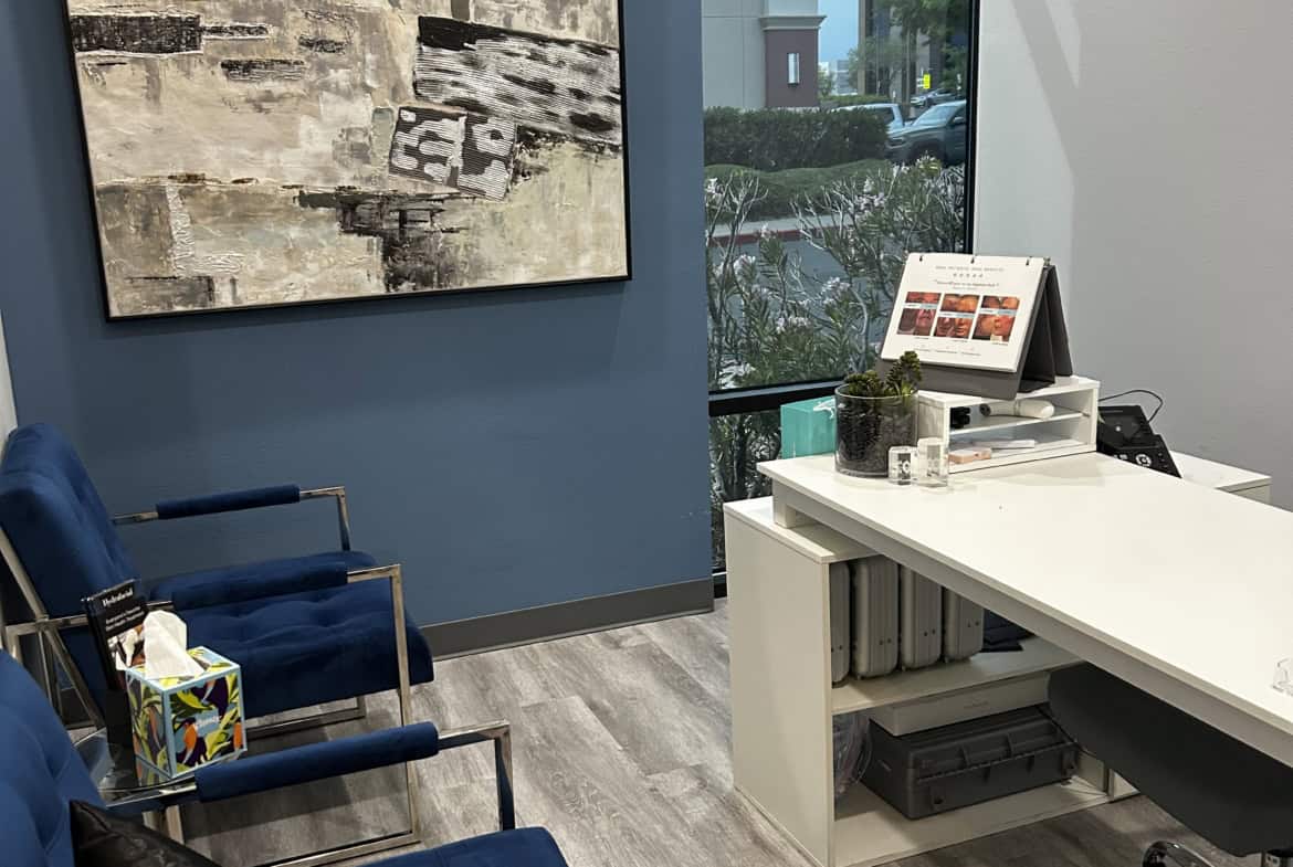 Reception area with comfortable blue chairs and abstract wall art in a salon.
