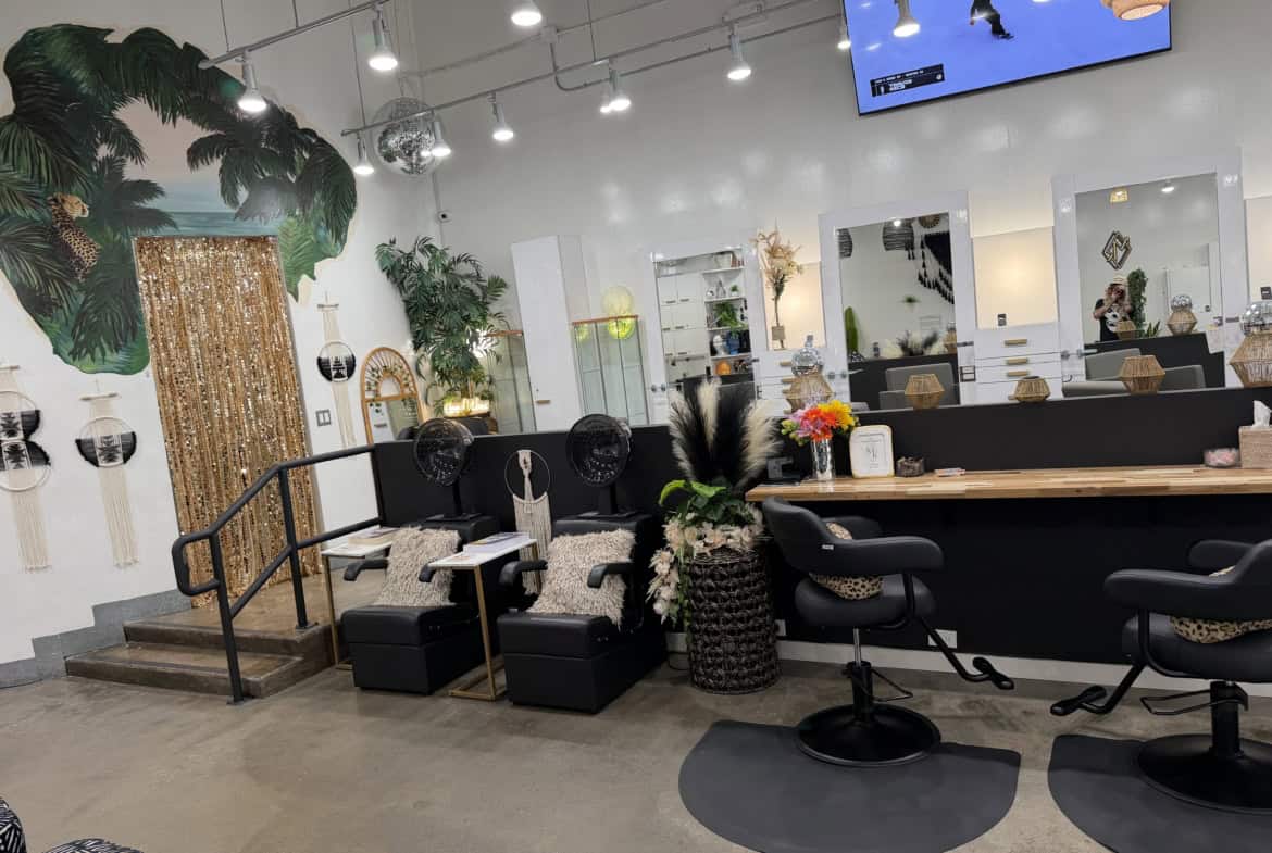 Stylish salon interior with seating, mirrors, and tropical decor elements.