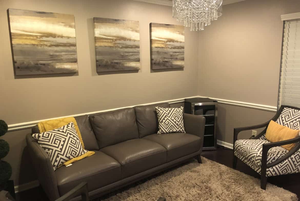 Comfortable salon renter lounge with sofa, armchair, and abstract wall art for clients and stylists.