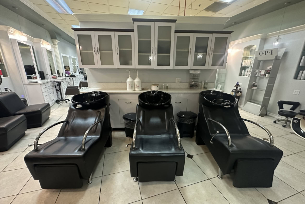 Modern hair washing stations in a salon with black chairs and white cabinetry.