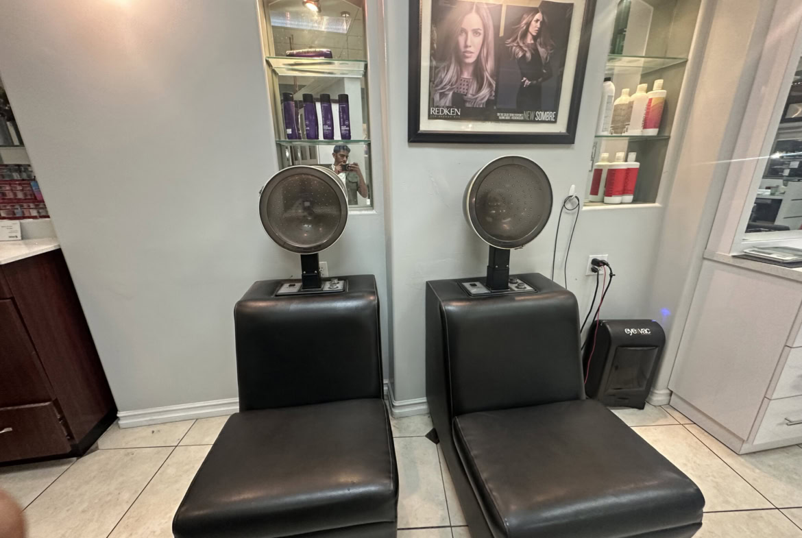 Two black hair salon chairs with headrests in a professional salon setting.