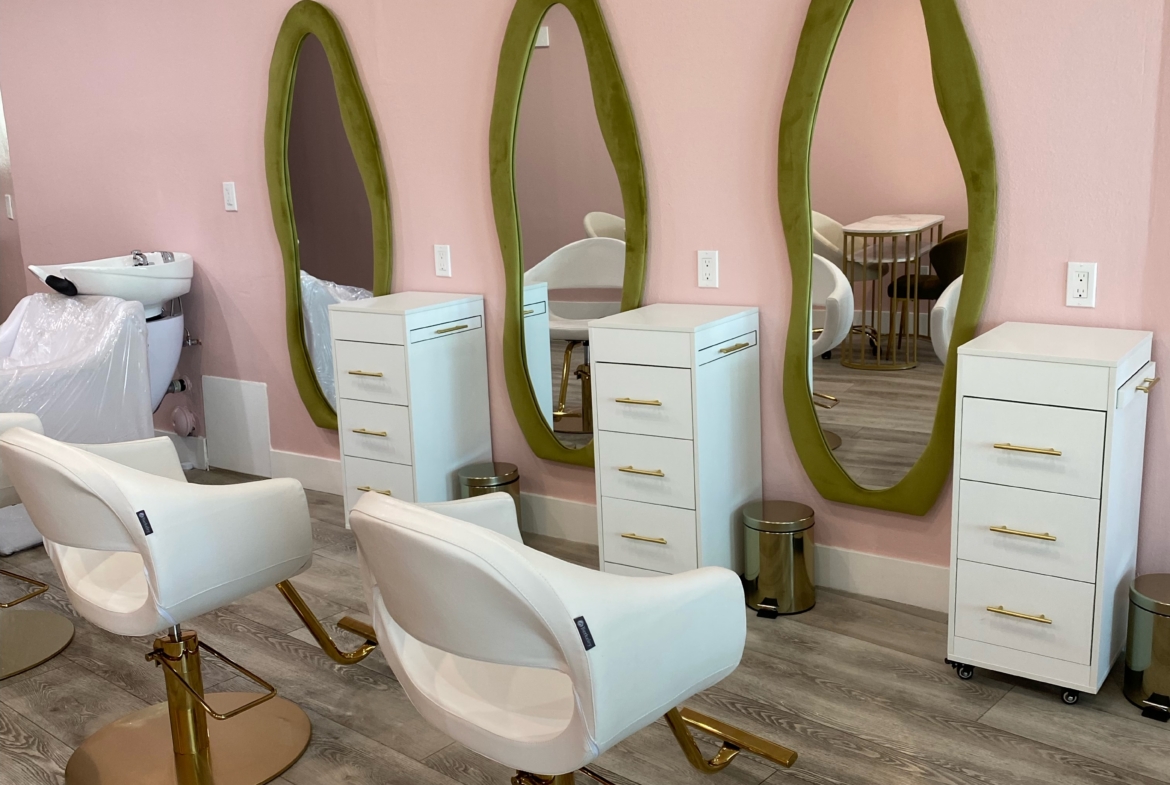 Modern salon styling stations with green-framed mirrors and white chairs.