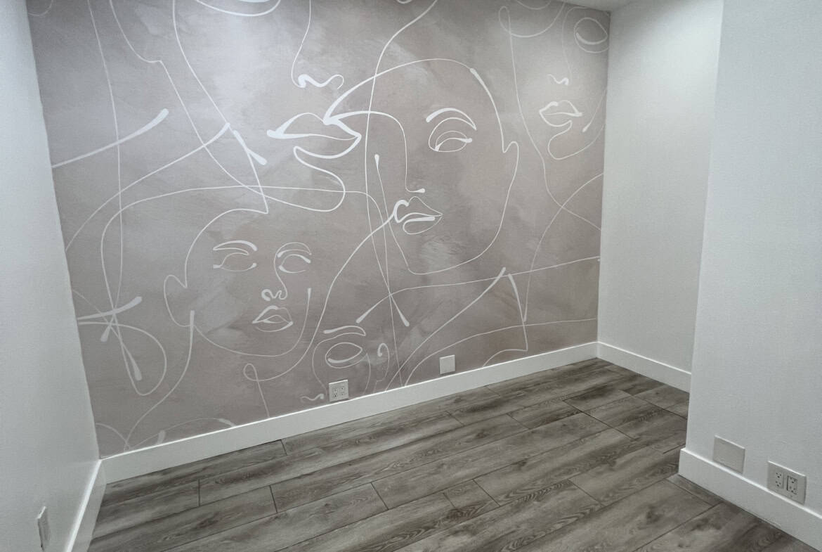 Contemporary salon space featuring abstract face art on wall and sleek flooring.