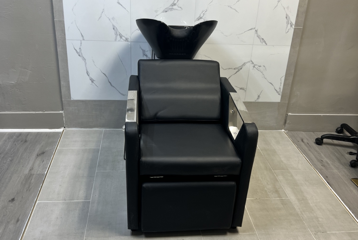 Professional hair washing chair with sink in salon setting.