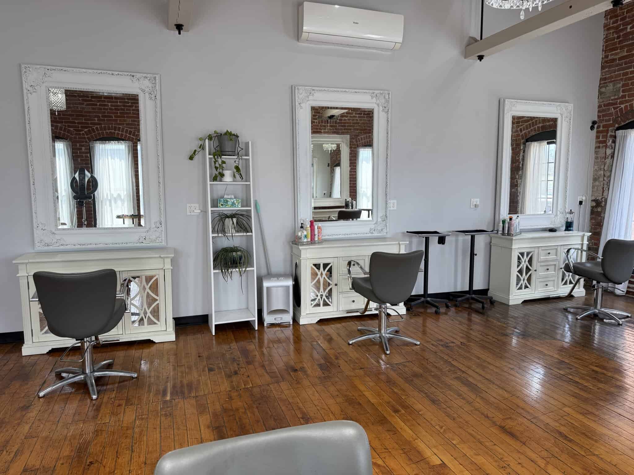 Stylish salon styling station with mirrors and chairs for hairdressing services.
