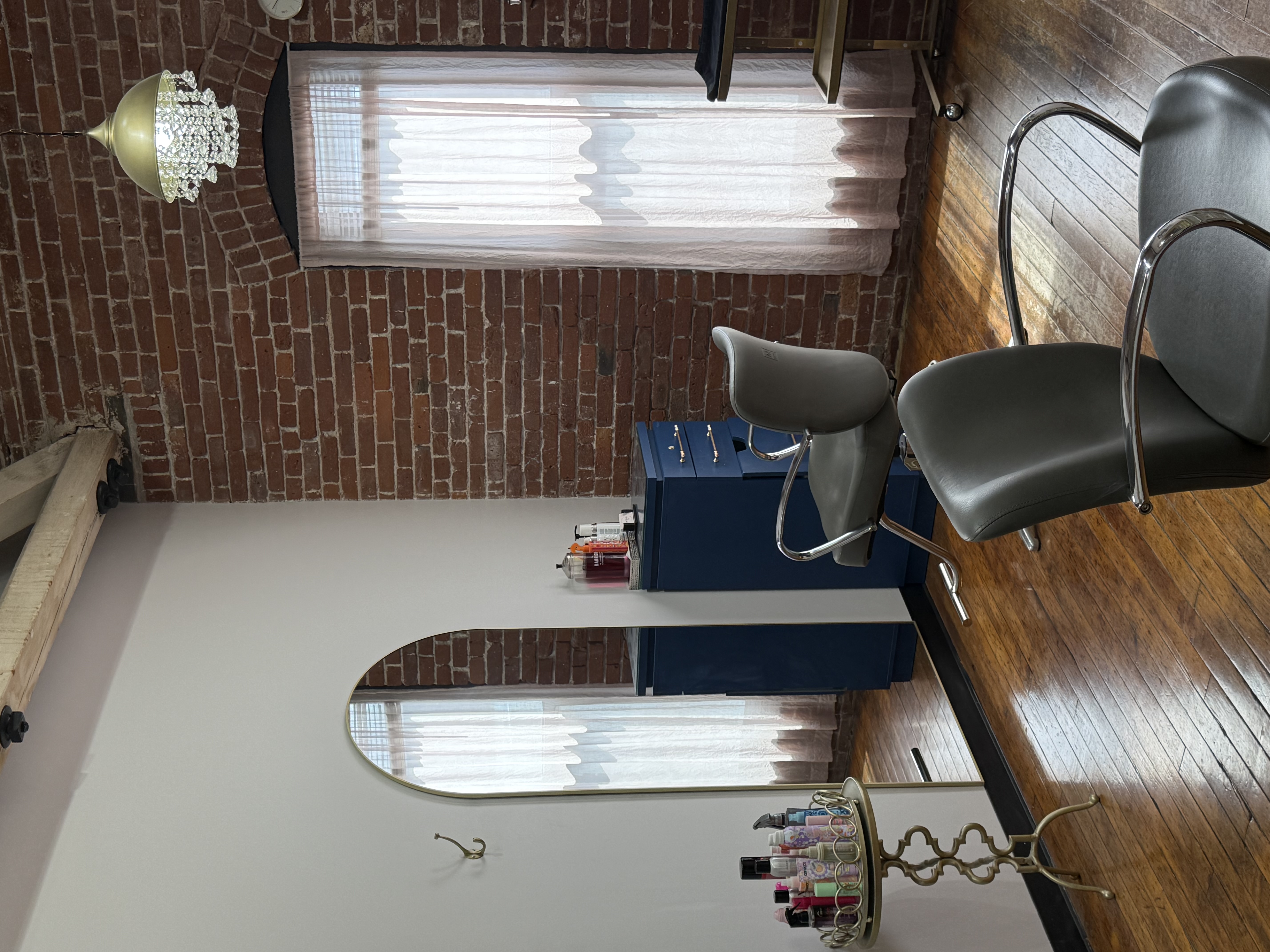 Salon Renter workspace with styling chairs, mirror, and brick wall decor.