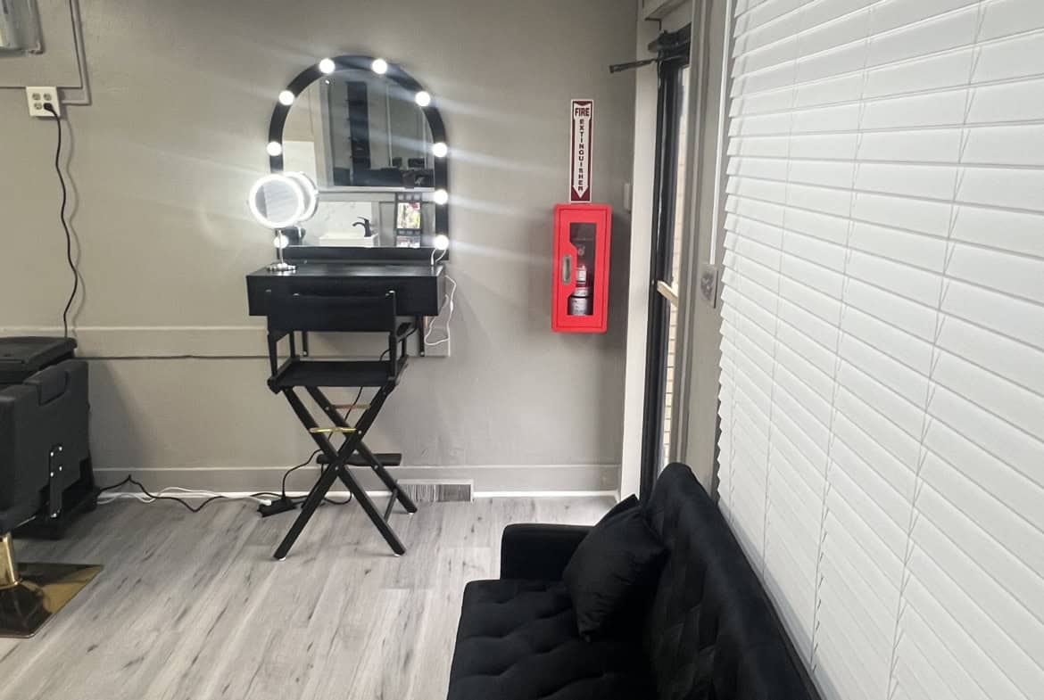 Modern salon styling station with illuminated mirror and black styling chair.