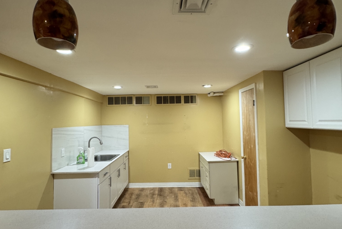 Bright salon kitchenette featuring white cabinetry, warm lighting, and a clean, functional space for.