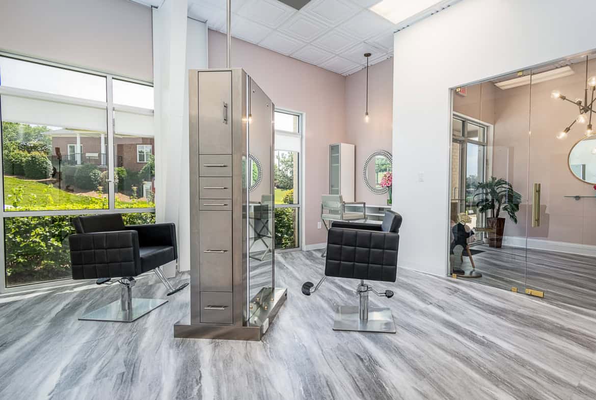 Stylish salon space with chairs, lockers, and large windows.