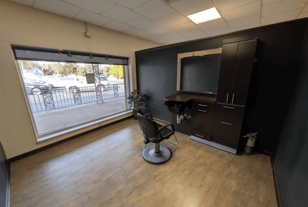 Hair salon station with large window, black storage cabinets, and styling chair.