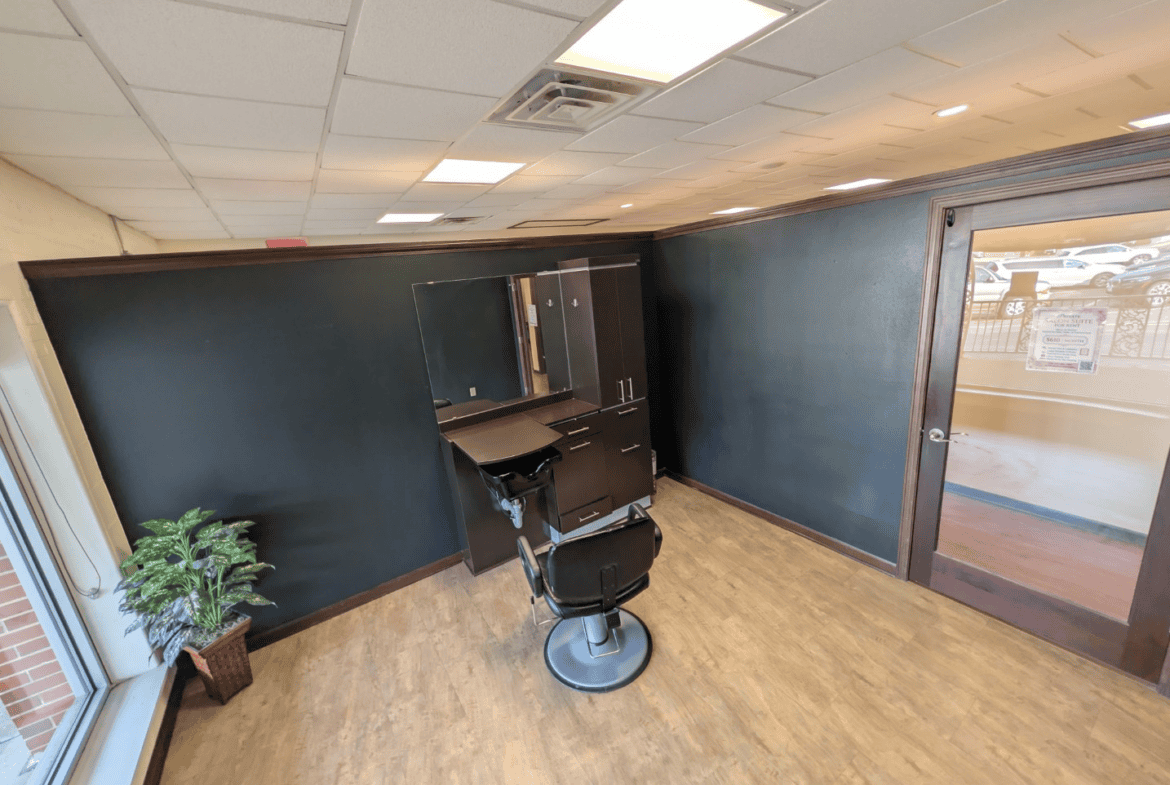 Empty salon room with styling chair, mirror, and dark blue walls, ideal for salon rental or beauty s.