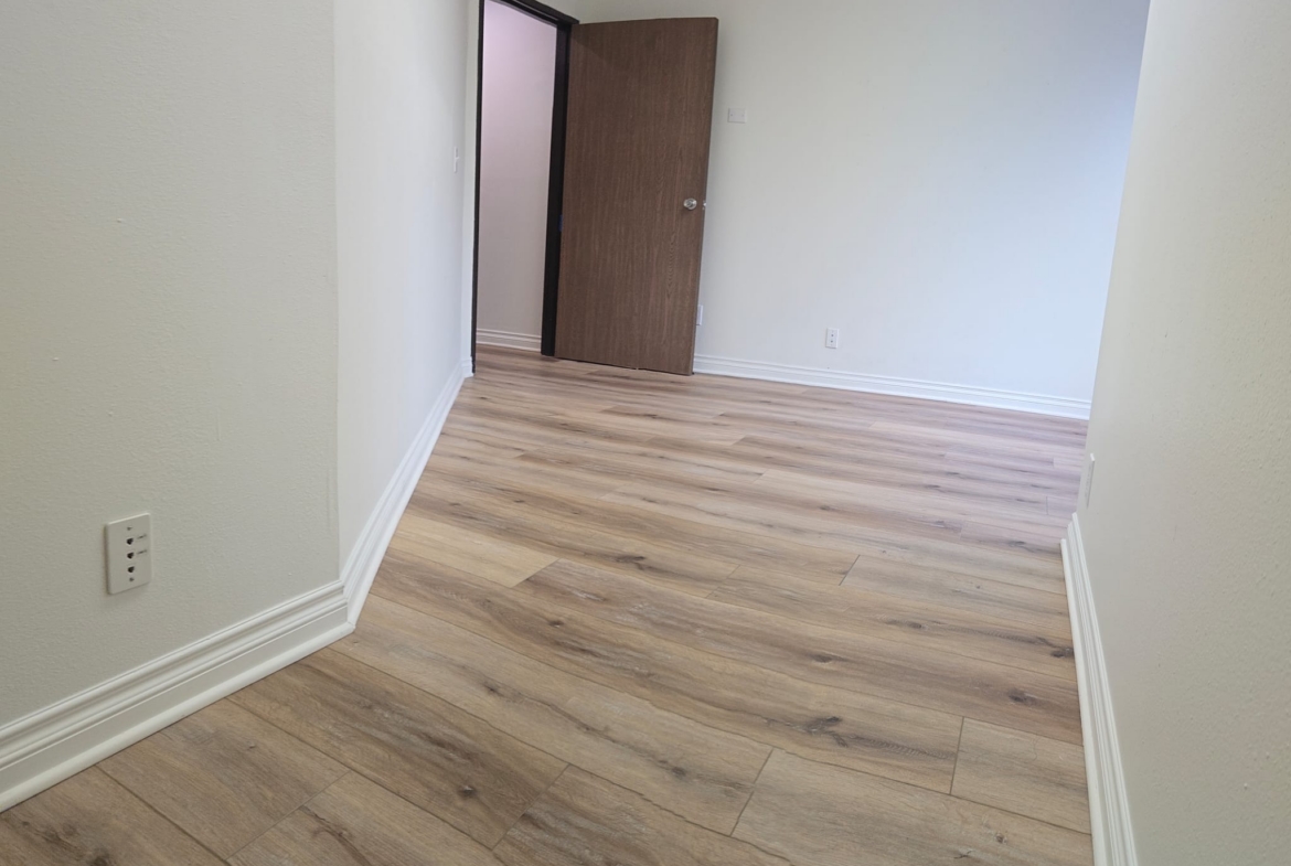 Empty salon room with wood flooring and open door, ready for styling.