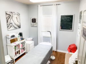 Cozy salon treatment room with massage table, storage, and welcoming decor.