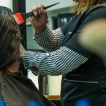 Hairdresser applying color to client's hair in salon setting.