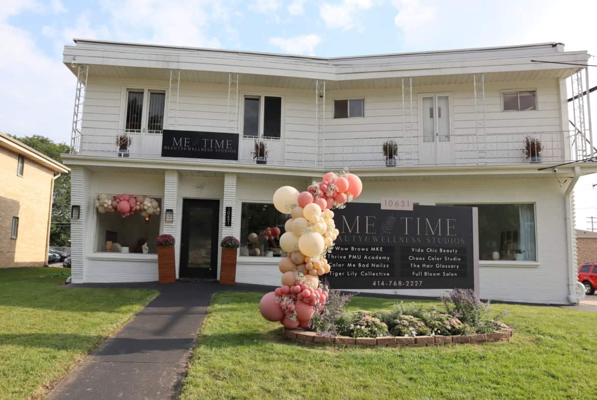 Modern white salon building decorated with pink and white balloons for grand opening.