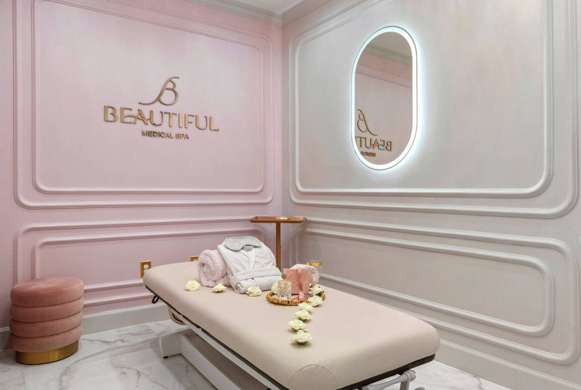 Luxurious spa treatment room with soft pink walls, chandelier, and massage table at Salon Renter.