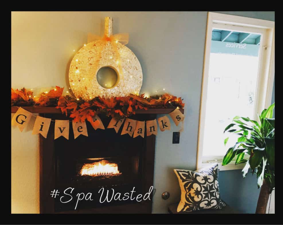 Festive Thanksgiving decoration featuring a wreath, fireplace, and "Give Thanks" banner in a cozy sa.