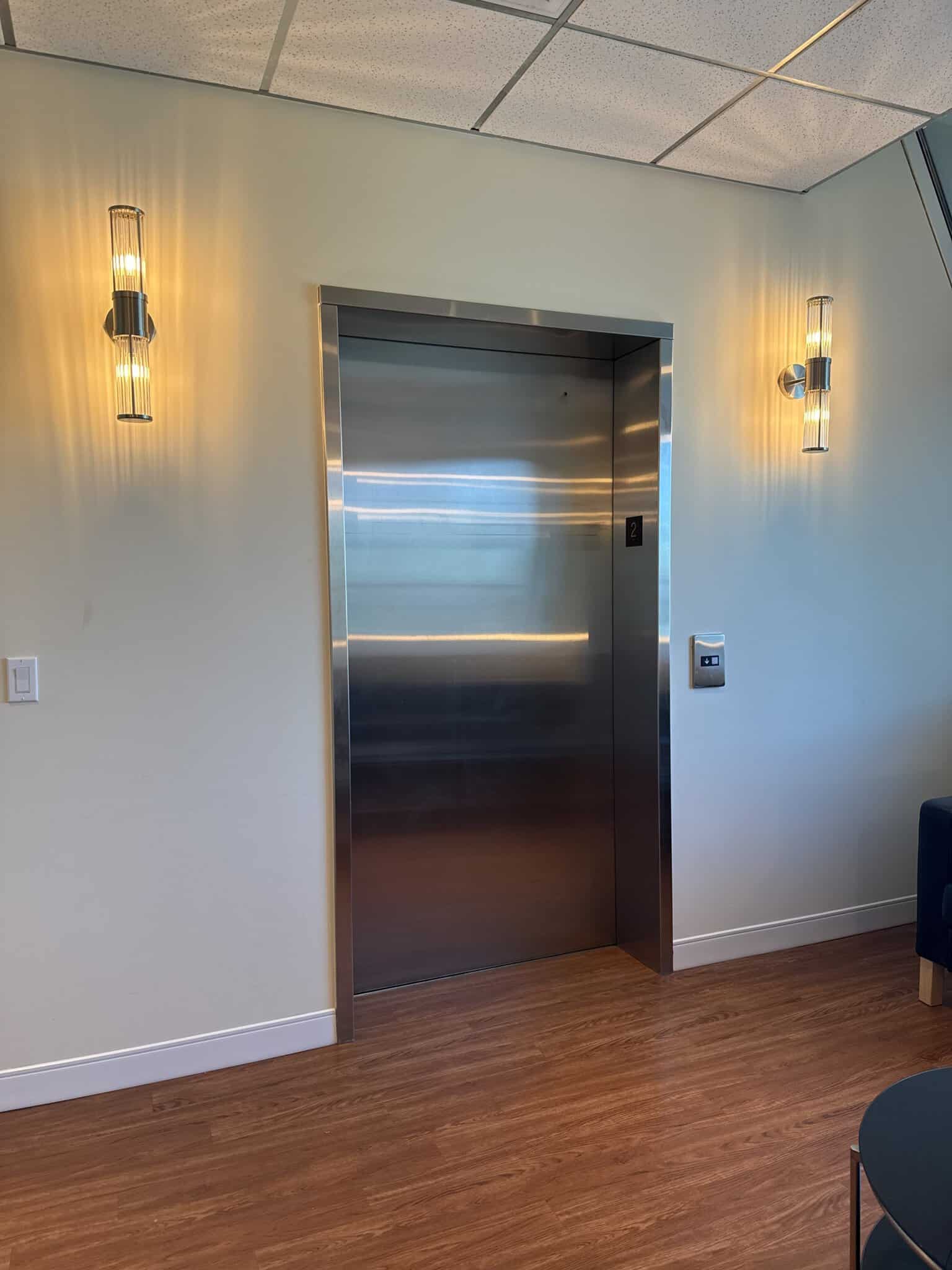 Elevator door with sleek stainless steel finish in a contemporary salon environment. Elegant wall sc.