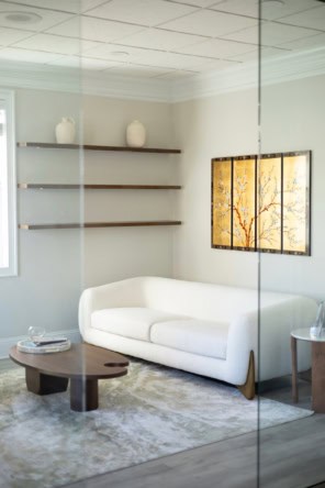 Contemporary salon waiting area featuring a white sofa, wall art, and minimalist decor.