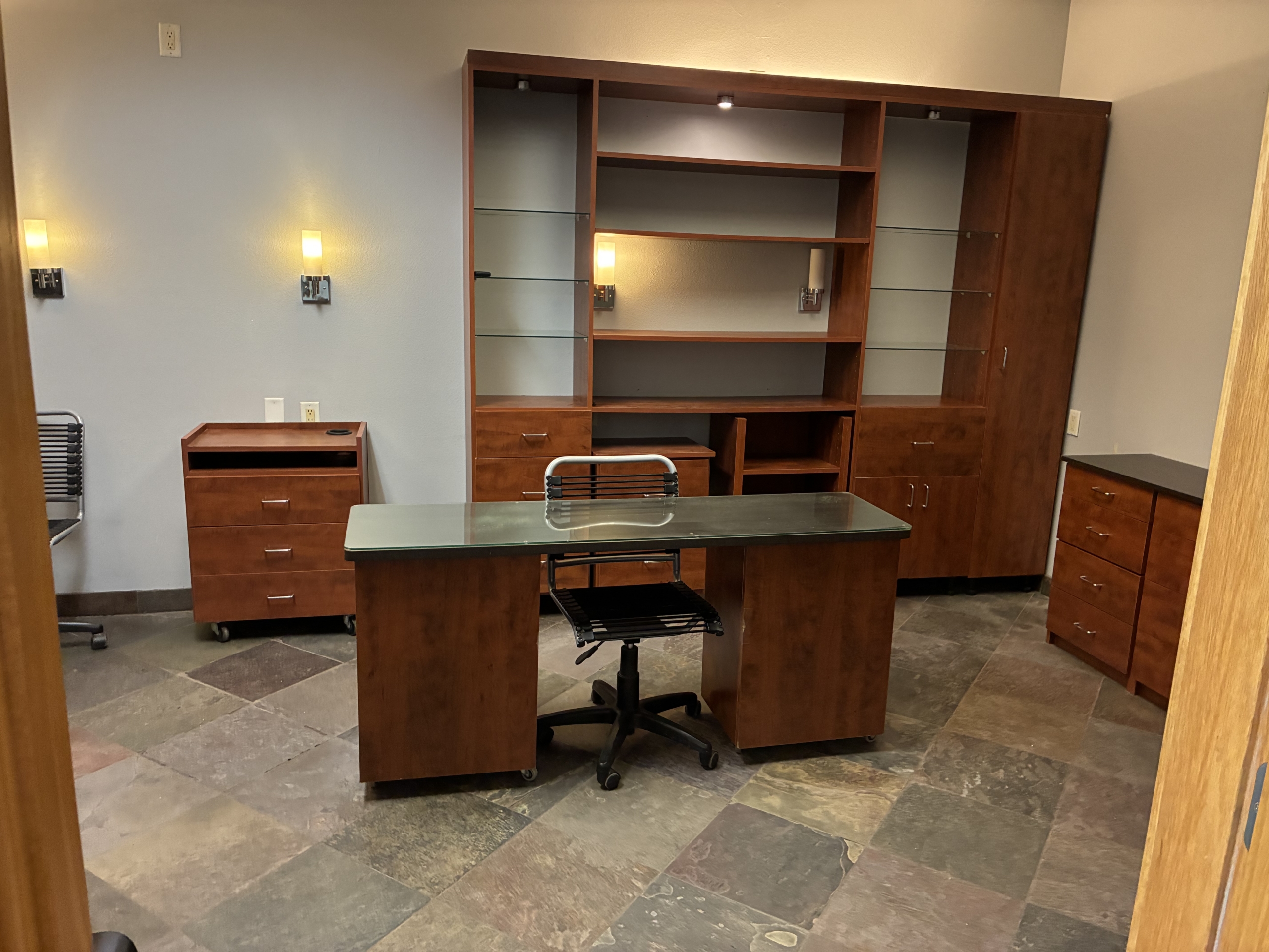 Modern salon renter office with wooden desk, shelves, and storage units.