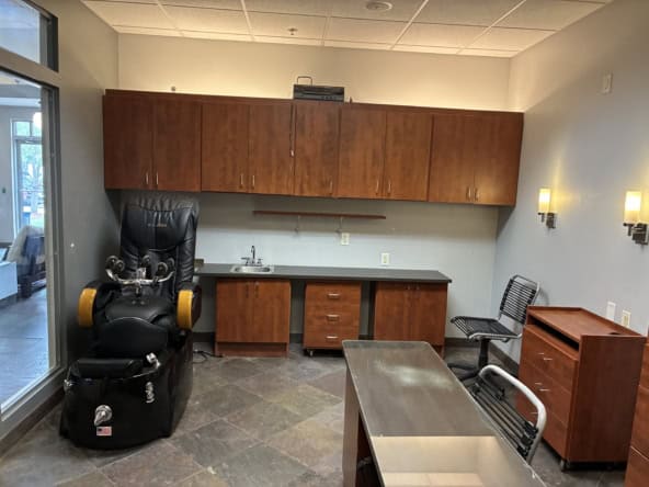 Modern salon office with massage chair, desk, and storage cabinets.