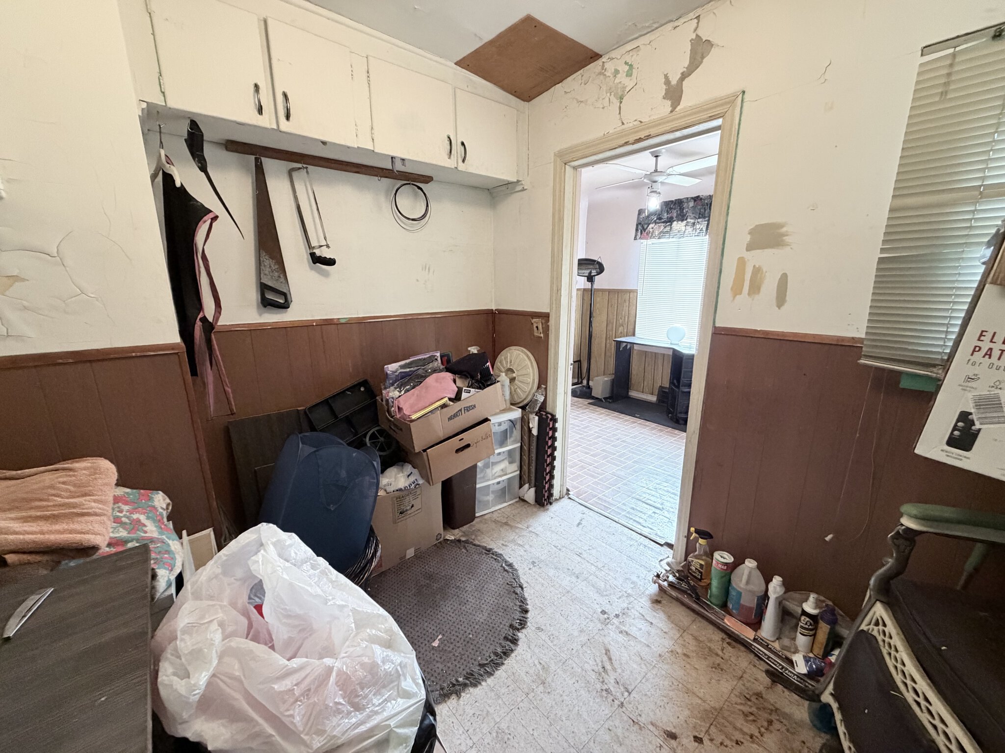 Interior of a cluttered salon storage room with cleaning supplies and miscellaneous items.