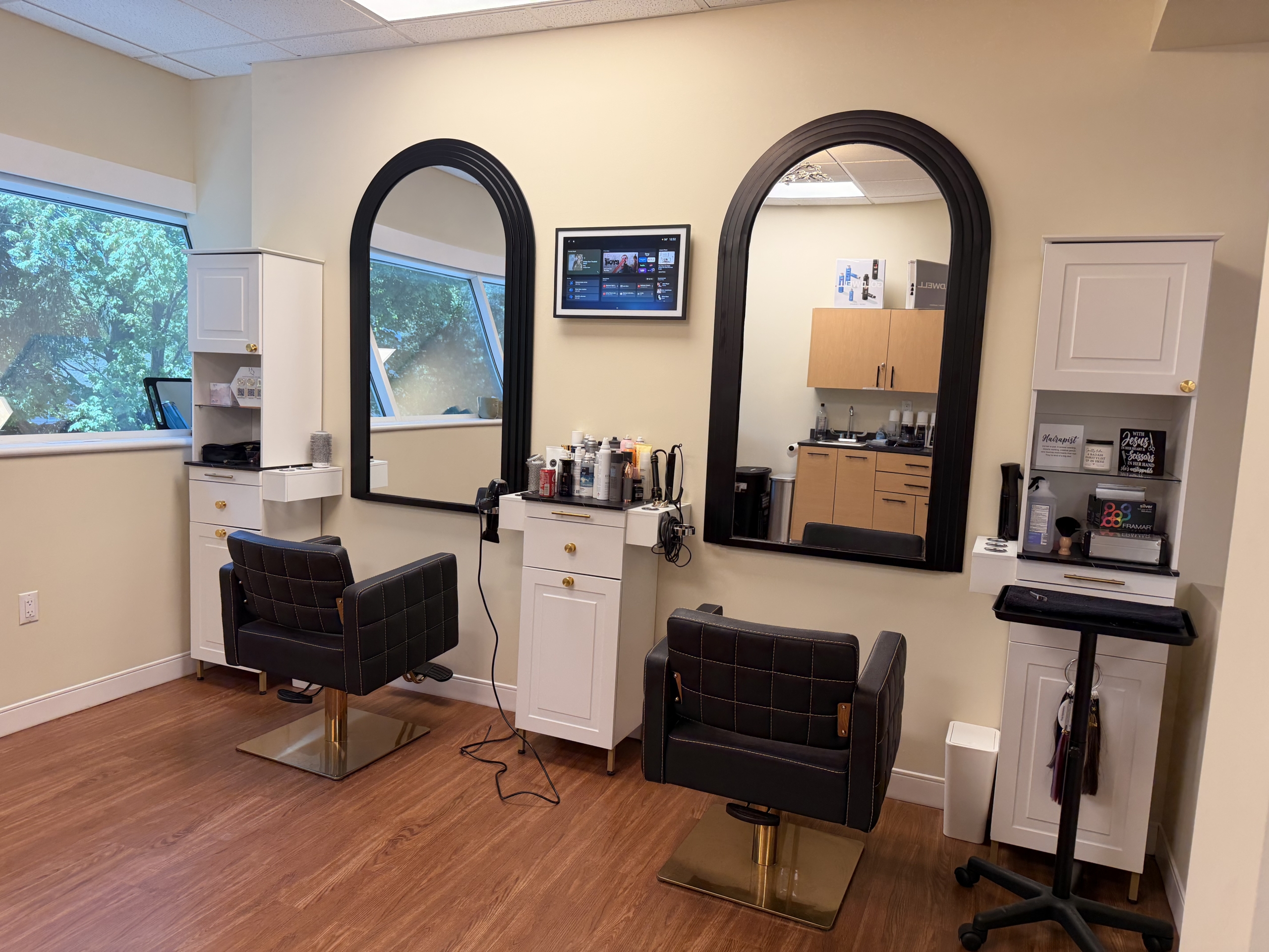 Modern hair salon station with two mirrors, styling chairs, and salon equipment.