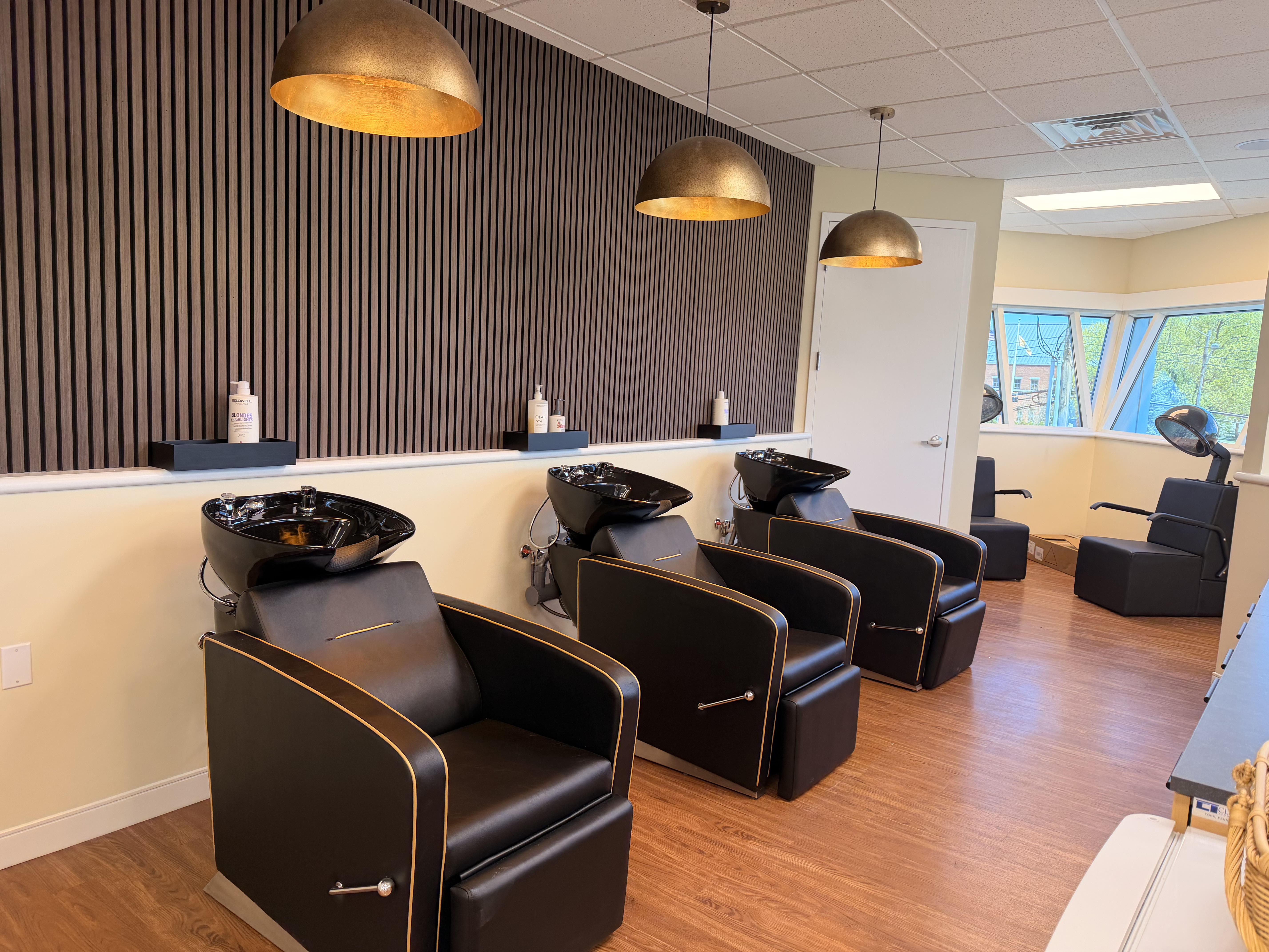 Salon Renter shampoo stations with black chairs and warm lighting.