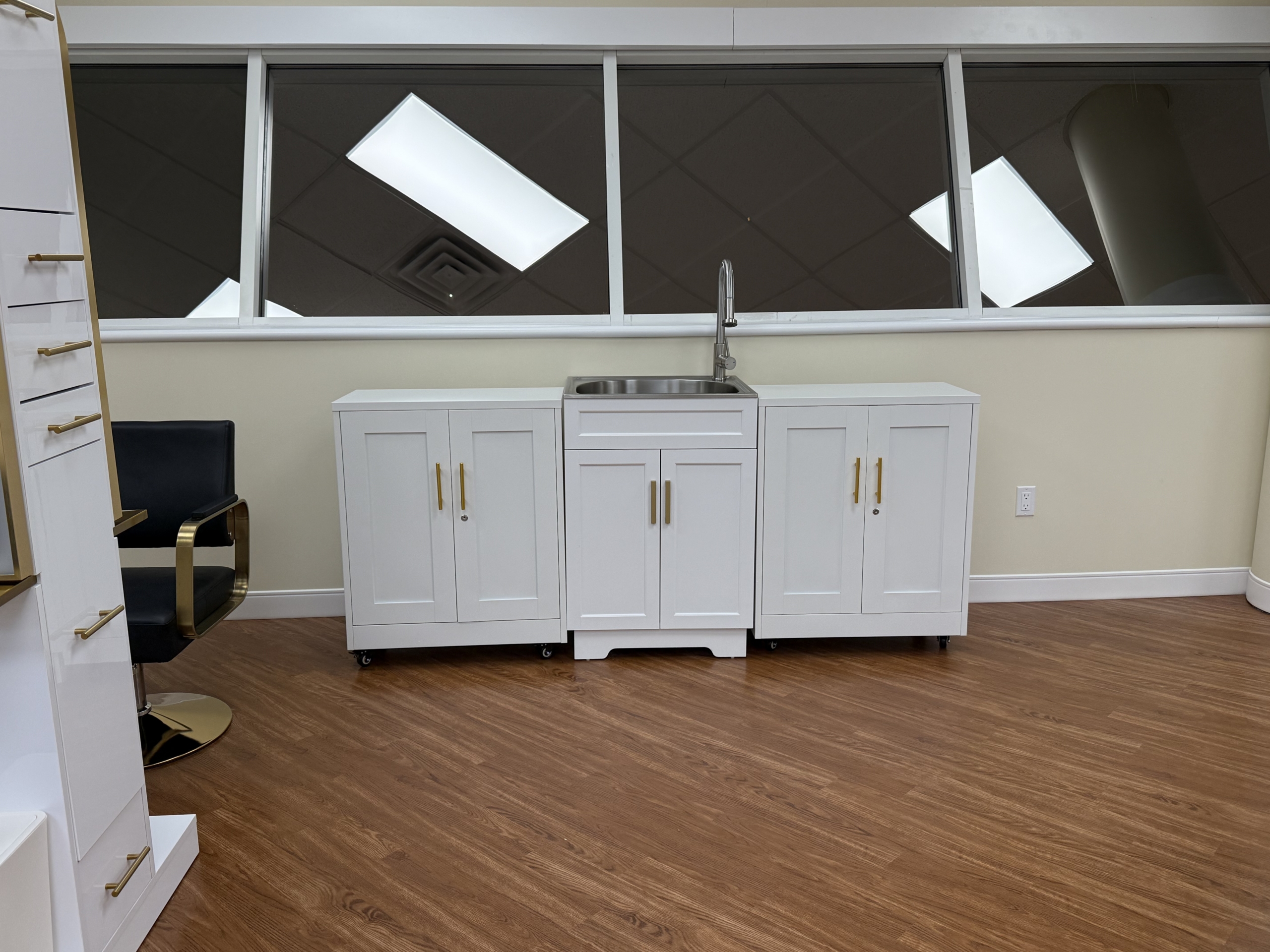 Modern salon sink with white cabinetry and large window in the background.
