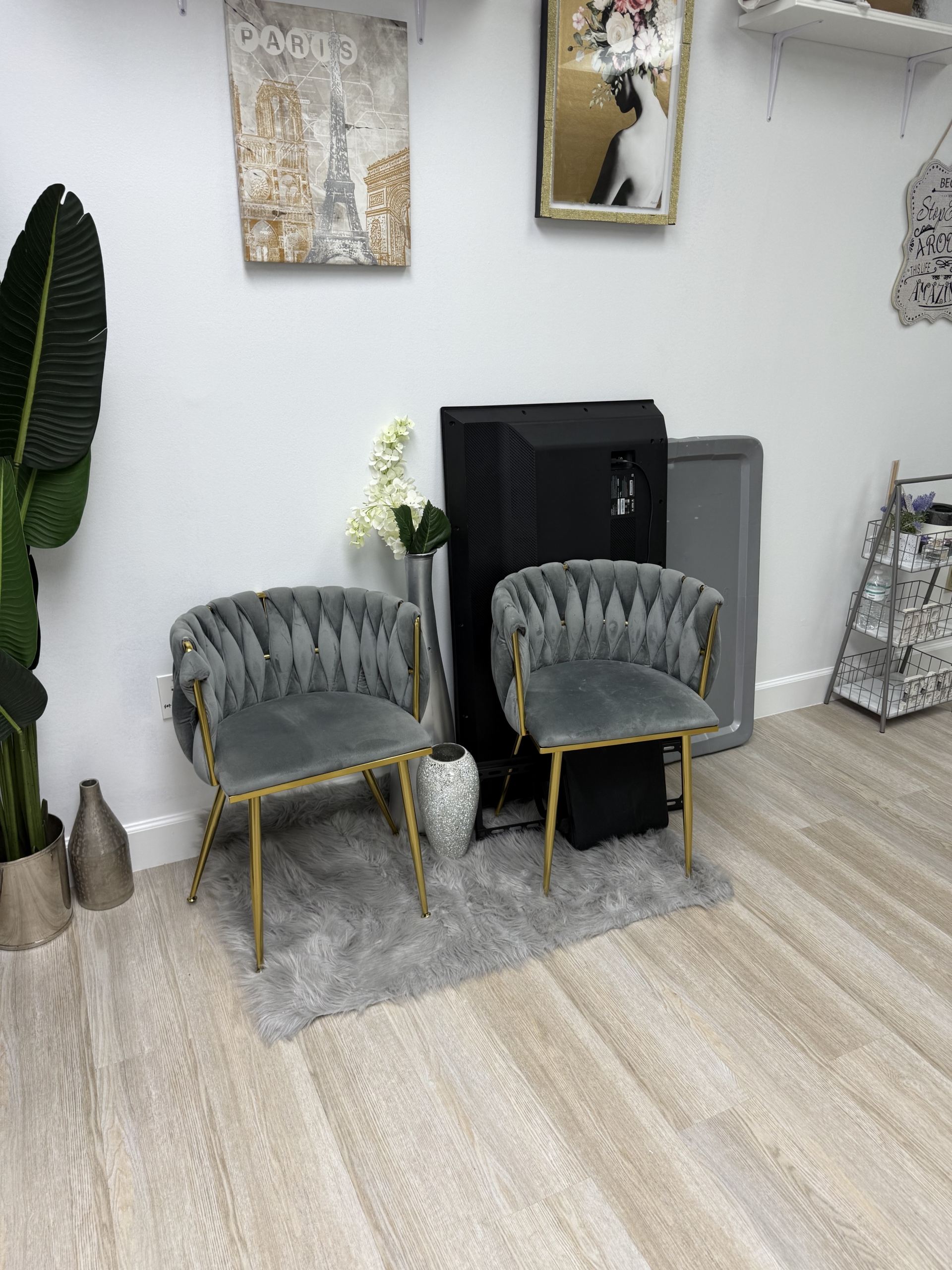 Elegant salon waiting area with plush gray chairs, wall art, and modern decor.