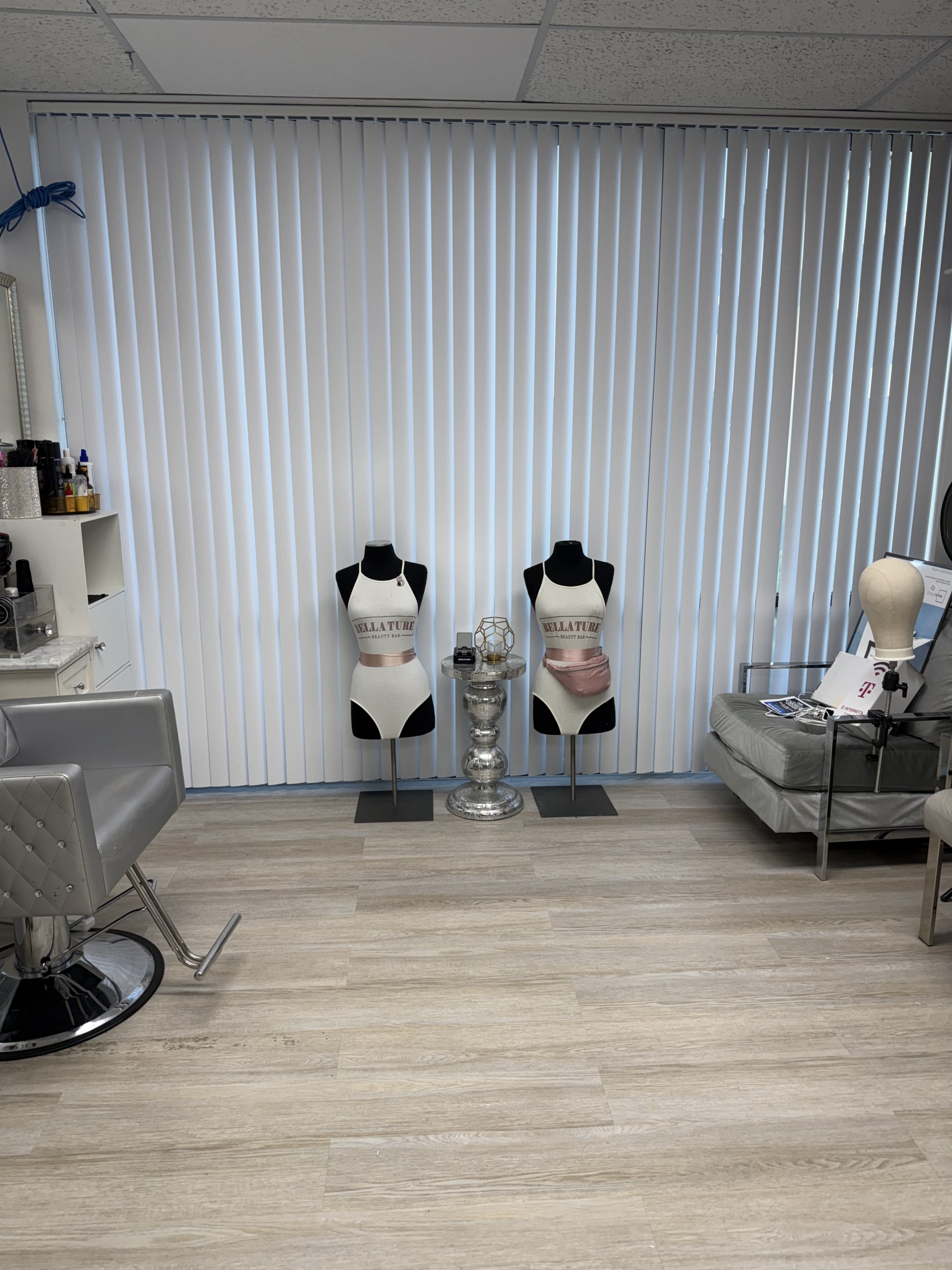 Interior of a beauty studio featuring two mannequins with hair and makeup displays, a styling chair,.