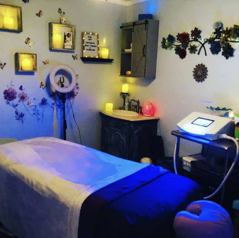 A calming massage room featuring soft lighting, floral wall art, and relaxing atmosphere for clients.