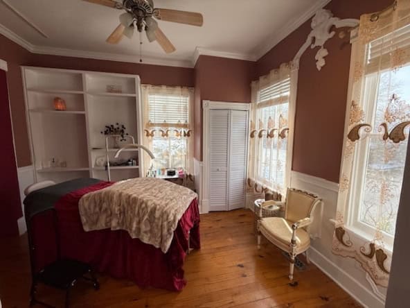 Cozy salon treatment room with large windows, vintage furniture, and warm wooden floors.
