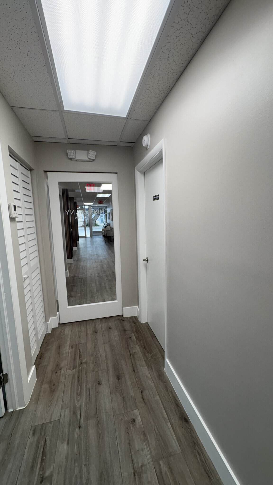 Bright salon hallway with modern decor, white walls, and wooden flooring, leading to styling station.