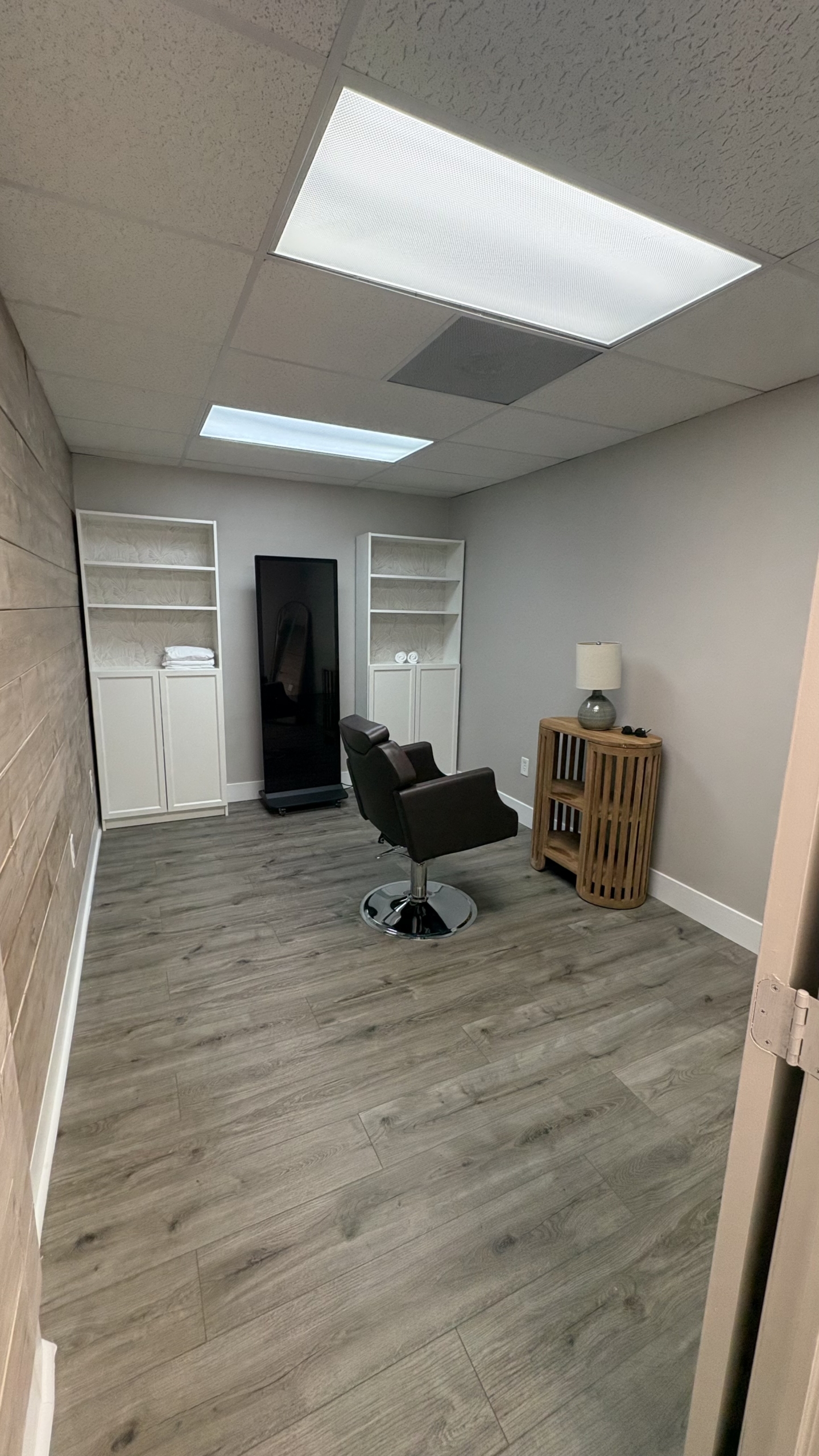 Bright salon room with styling chair, shelves, and ceiling lights for professional hair services.