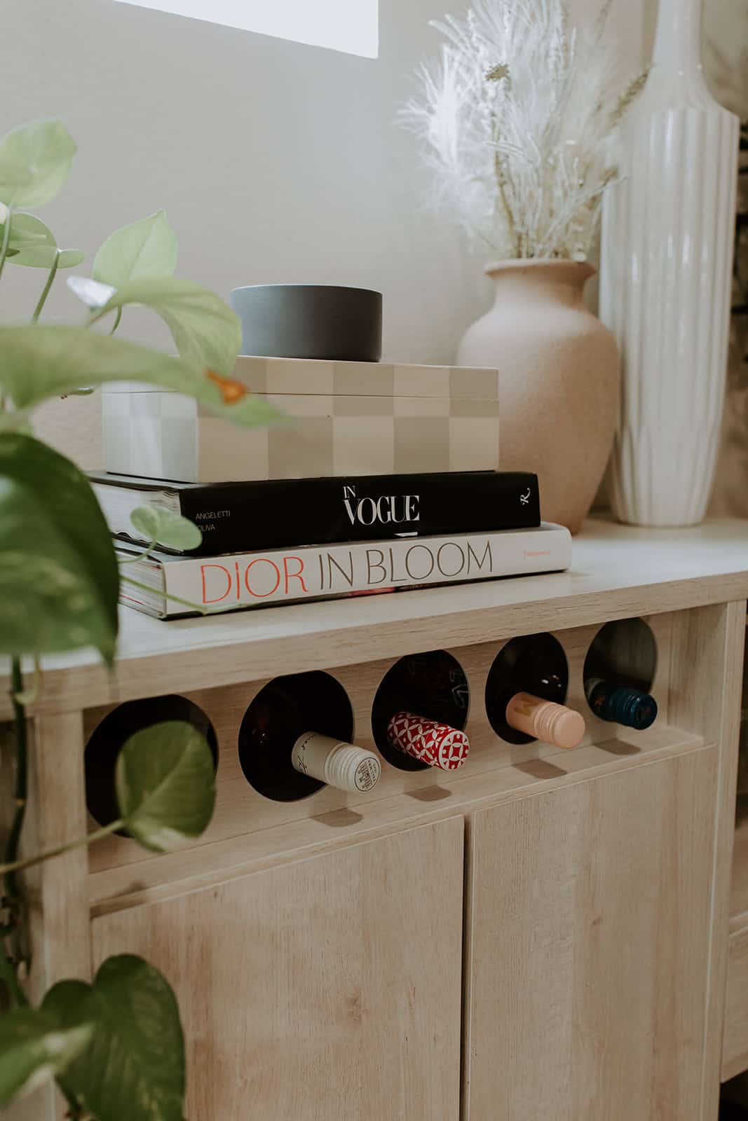 Stylish salon storage unit with wine bottle holders, decorative vases, and fashion books.