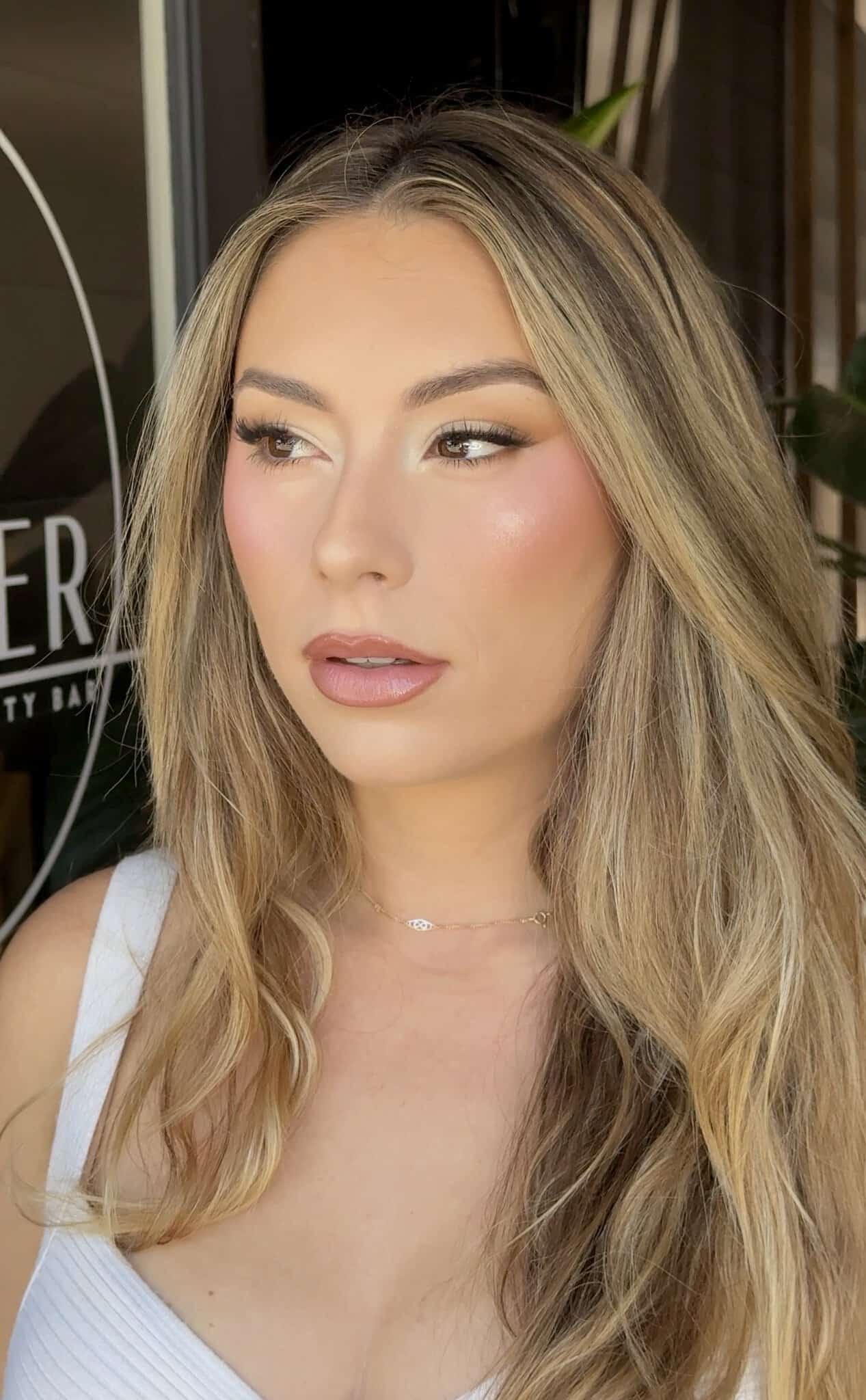 Blonde woman with wavy hair and natural makeup at Salon Renter, showcasing professional hair styling.